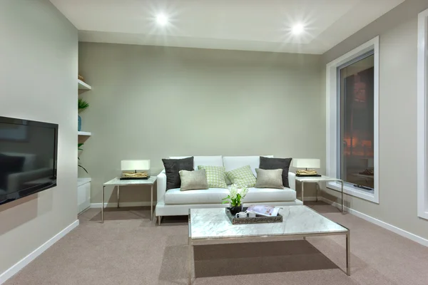 Uma sala de estar com uma pequena mesa branca e almofadas no sofá — Fotografia de Stock