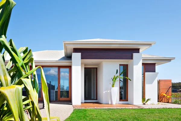 Villa modern dengan halaman dekat pohon daun panjang dan langit biru — Stok Foto