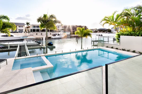 Развлекательная зона современного многомиллионного дома, бесконечный бассейн с видом на канал, когда заходит солнце — стоковое фото