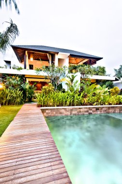 Wooden pathway to a modern house through a garden 