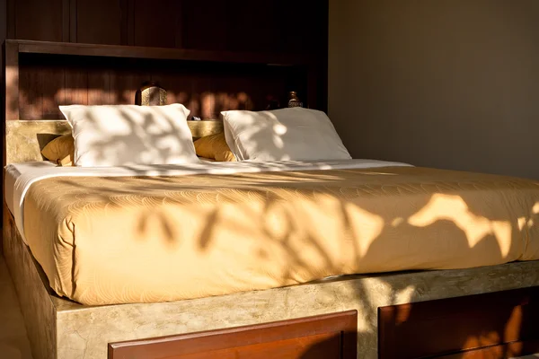 Крупный план деревянной кровати и подушек, освещенных солнечным светом — стоковое фото