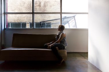 Bir kanepe ve görünüm uzağa--dan pencere eşiği üstünde oturan kız