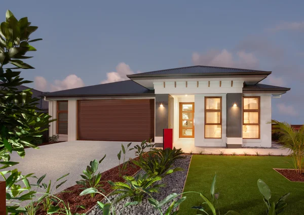 Luxury house with a green grass garden illuminated at night — Stock Photo, Image