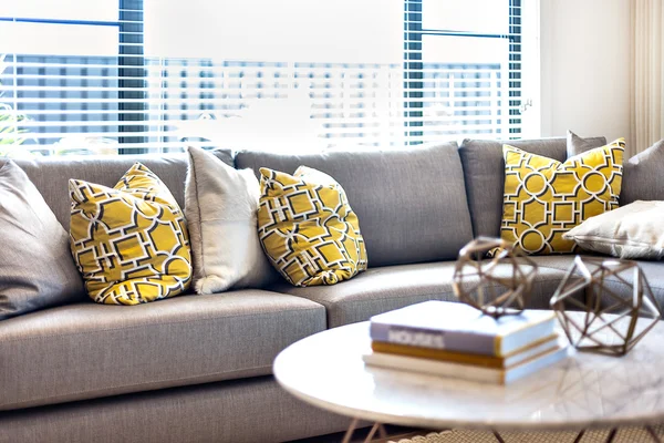 Travesseiros no sofá cinza ao lado de uma janela e luz solar — Fotografia de Stock