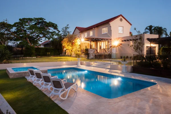 Piscina moderna com uma grande casa iluminada com luzes — Fotografia de Stock