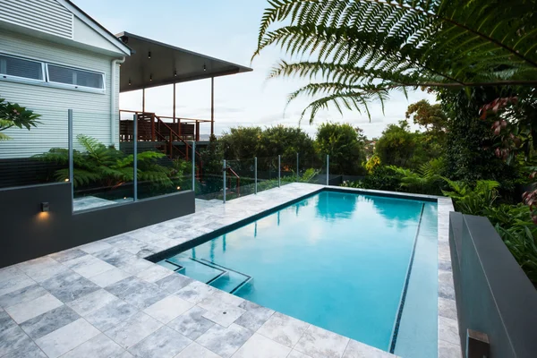 Piscina de agua azul con baldosas bajo árboles verdes — Foto de Stock