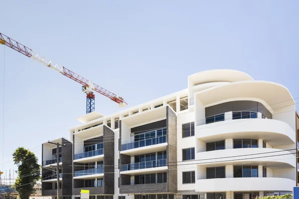 Modern building finishing with a crane under blue sky — Stock Photo, Image