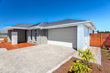 Modern ev garaj ve arka bahçesinde bir alan ve mavi gökyüzü ile