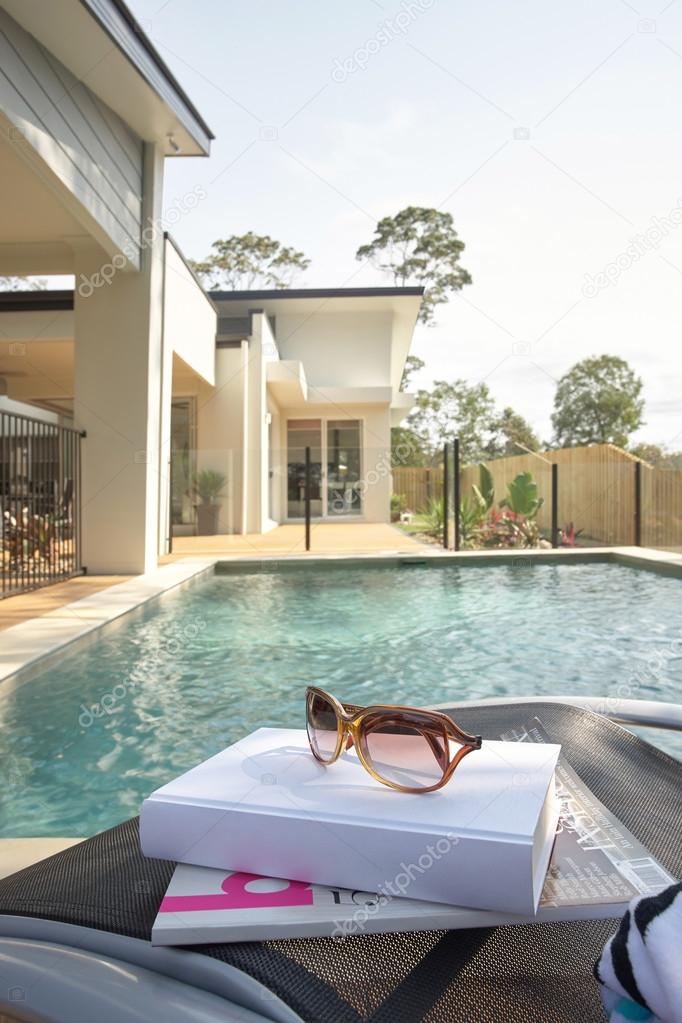 Sunglasses with book on chair at poolside