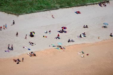 Kumsalda güneşlenirken insanlar