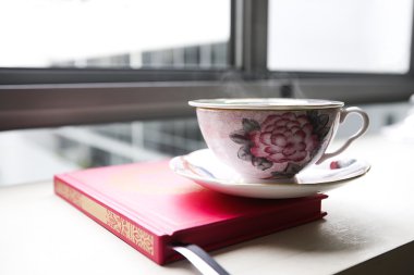 Buharlı çay bardağı, bir kitap üzerine yerleştirilen