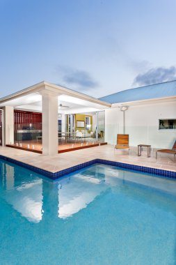 Modern swimming poll in the night with a luxury mansion or hotel
