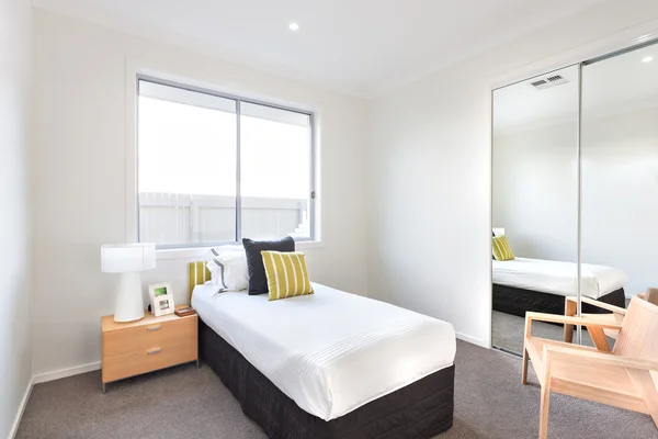 Chambre moderne avec un lit simple et draps blancs près d'un miroir — Photo