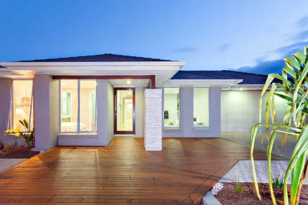 Front of the lights turned on modern mansion with wooden floor a — Stock Photo, Image