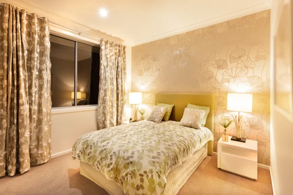 Современная спальня с двуспальной кроватью освещается настольными лампами — стоковое фото