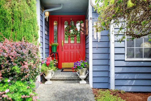 Heldere voorkant rode deur naar blauwe Amerikaanse Huis met bloemen buitenkant — Stockfoto