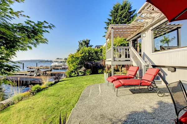Waterfront back yard, Furnished back patio with red chairs, and — Stock Photo, Image