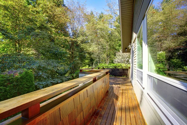 Casa gris con porche de madera soleado con barandilla grande . — Foto de Stock
