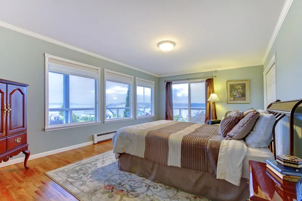 Dormitorio principal de lujo con paredes azules, cama grande marrón y suelo de madera . —  Fotos de Stock