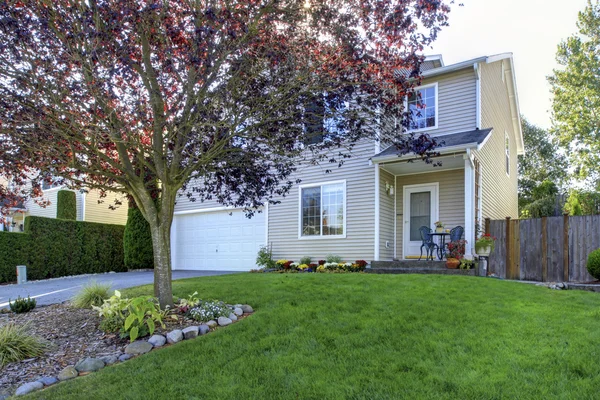 Adorable casa blanca con bonito césped delantero y árboles . — Foto de Stock