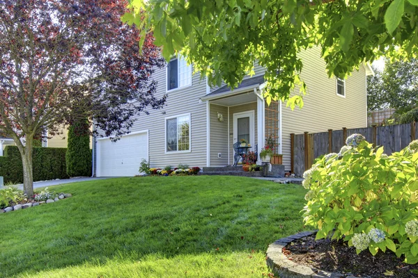 Adorable casa blanca con bonito césped delantero y árboles . — Foto de Stock