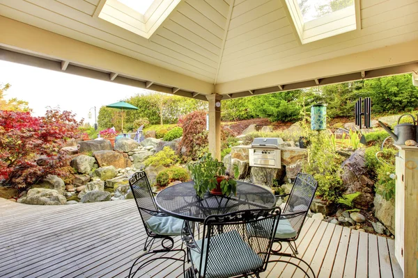 Covered deck with sunroof windows, grill and metal outdoor furniture. — Stock Photo, Image