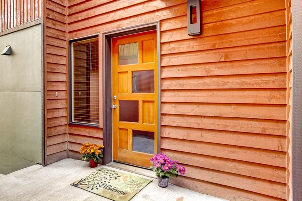 Front door with open porch, decorated with flower pots