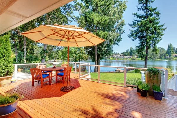 Sitzecke auf abgeschirmtem Walkout-Deck mit Terrassentisch, Sonnenschirm und Stühlen. — Stockfoto