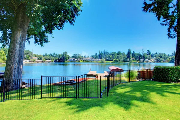 Backyard area with well kept lawn and metal fence. Beautiful water view — Stock Photo, Image