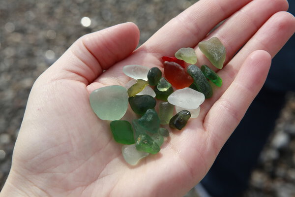 Green, brown, white seaglass in the hand 