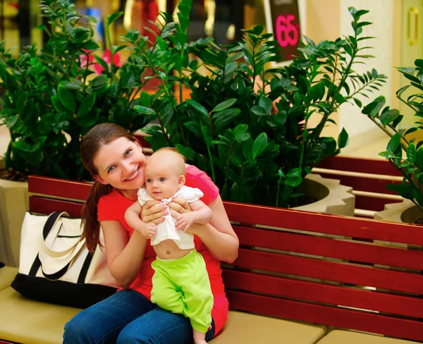 Shopping di famiglia. Giovane madre e sua figlia in panchina . — Foto Stock