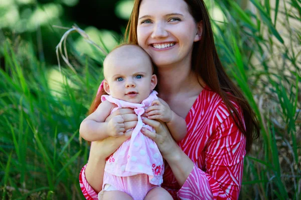 Schöne glückliche Mutter hält Baby-Mädchen mit Liebe — Stockfoto
