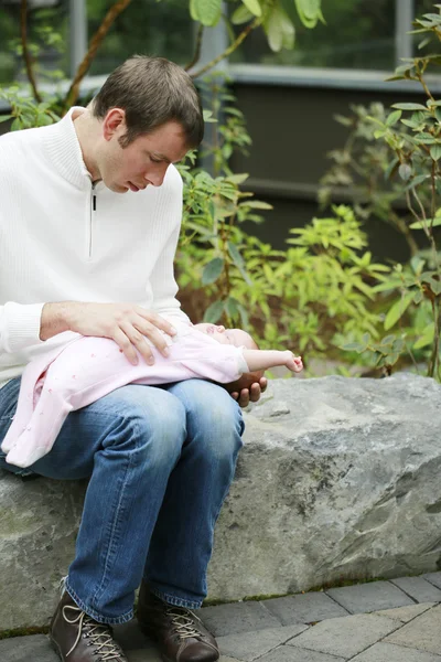 Baby girl lies on the father's lap outdoor — Stock Photo, Image