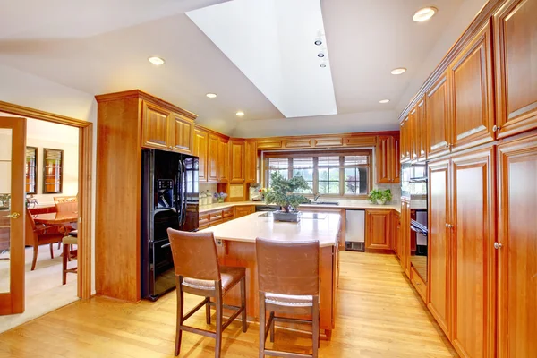 Intérieur de cuisine en bois marron avec réfrigérateur intégré noir et plafond blanc avec puits de lumière . — Photo