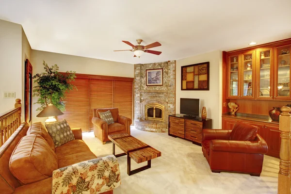 Cozy upstairs living room in brown tones with stone fireplace in the corner. — Stock Photo, Image