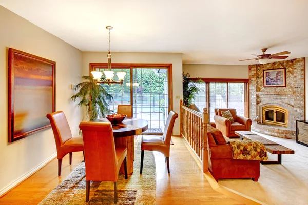 Casa com plano aberto. Vista da sala de jantar com conjunto de mesa e lareira de tijolo na sala de estar . — Fotografia de Stock