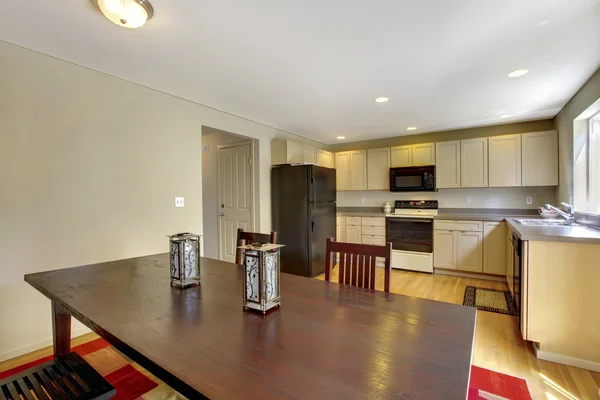 Luminosa sala de cocina con armarios beige y electrodomésticos negros . — Foto de Stock