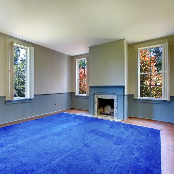 Unmöbliertes Wohnzimmer mit antikem Kamin und blauem Teppich. — Stockfoto