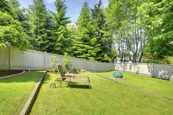 Área verde patio trasero con valla de madera y sillas — Foto de Stock