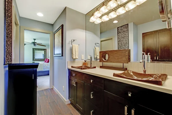 Niebieska i brązowa łazienka wnętrze z czarnych brązowych szafek i duże lustro. — Zdjęcie stockowe