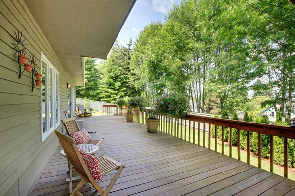 Wooden walkout deck with chairs and flower pots . — Stockfoto