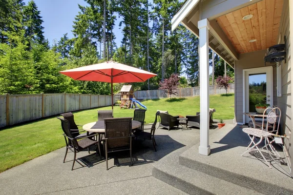 Amplia zona de patio cercado con mesa de patio y juego para niños — Foto de Stock