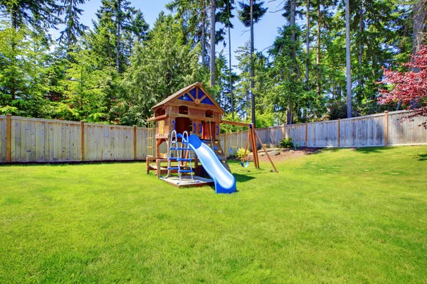 Çitle çevrili arka bahçesinde paraşüt ile çocuk zemin alanı oynayın. — Stok fotoğraf