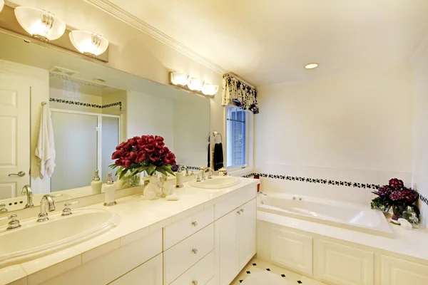 Елегантний білий інтер'єр ванної кімнати прикрашений квітами . — стокове фото