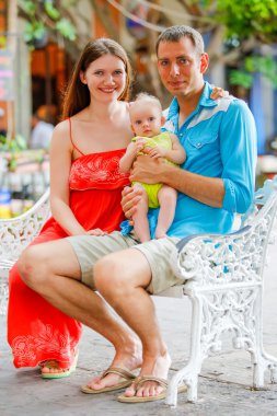 Onların sevimli bebek kız ile bir bankta oturan Sevgi dolu çift