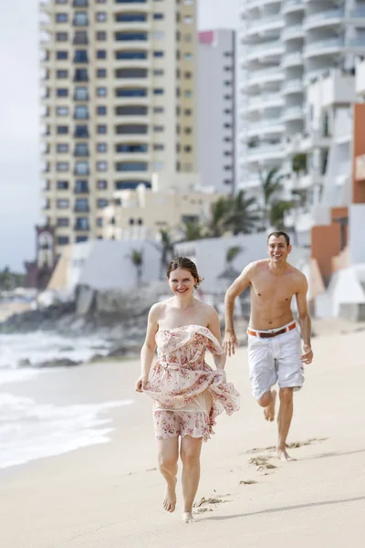 Una atractiva pareja corriendo por la playa — Foto de Stock