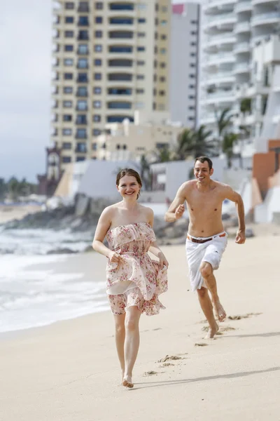 Ett attraktivt par som springer längs stranden — Stockfoto