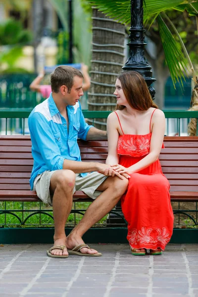 Young happy couple sitting on a wooden bench — 图库照片