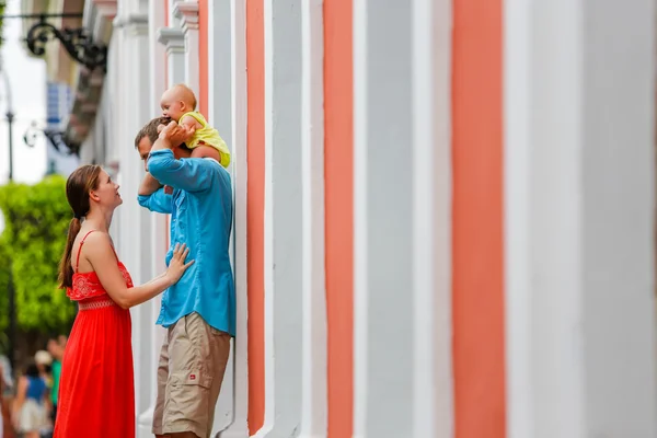En familj på tre stående bakom muren utanför. — Stockfoto