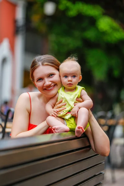 Портрет счастливой матери, сидящей на скамейке со своей малышкой — стоковое фото